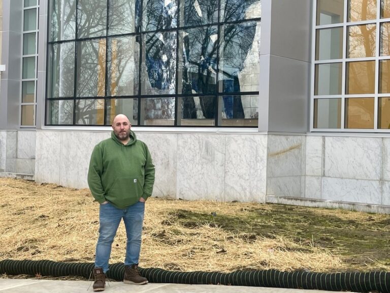 ray boila standing in front of mural