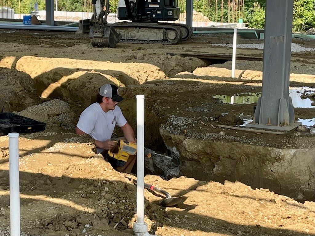 PJ Beres, apprentice at Boot Electric, clears dirt for the pathway for the underground conduit pipe at the health and wellness expansion.