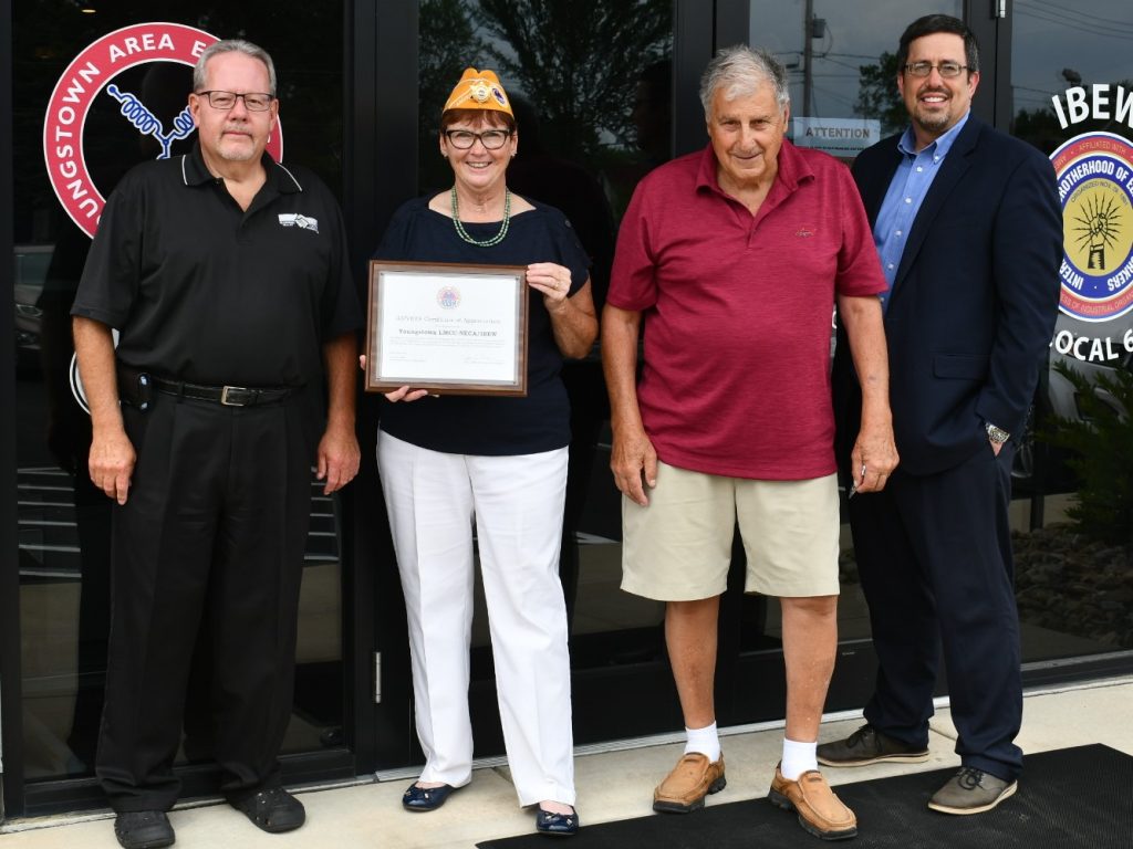 electricians and Jan Brown holding plaque